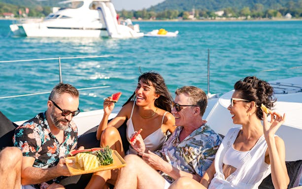 Friends enjoying fresh fruit on a catamaran sailing trip.