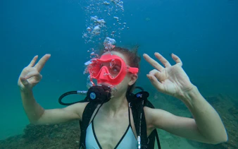 Scuba diver underwater in Fujairah showing OK sign during Abu Dhabi day trip.