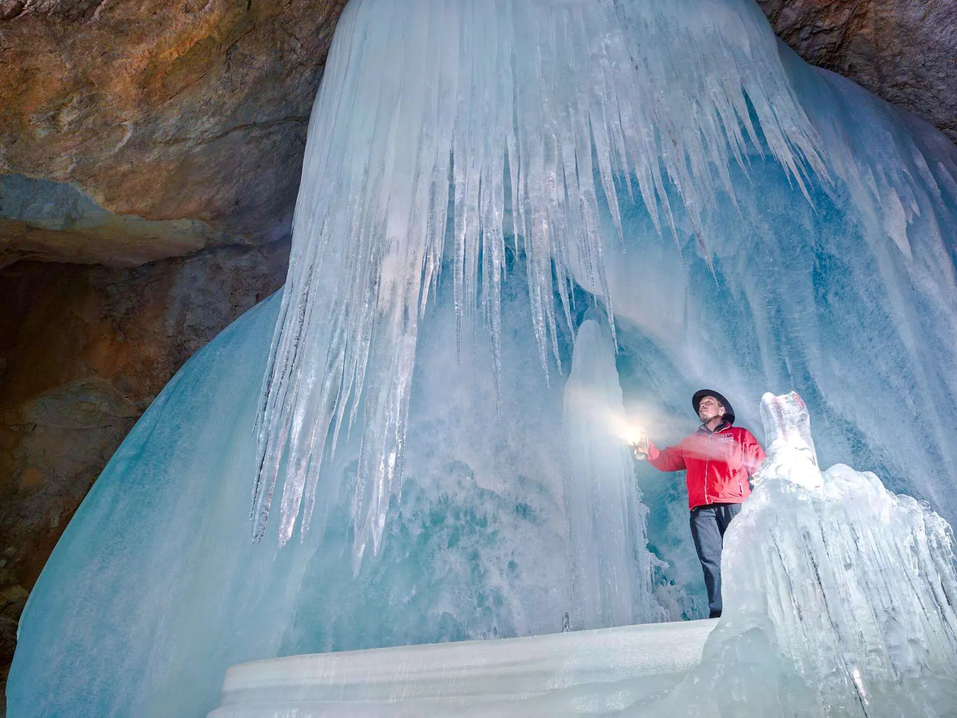 Person exploring Werfen Ice Caves with flashlight, Salzburg.