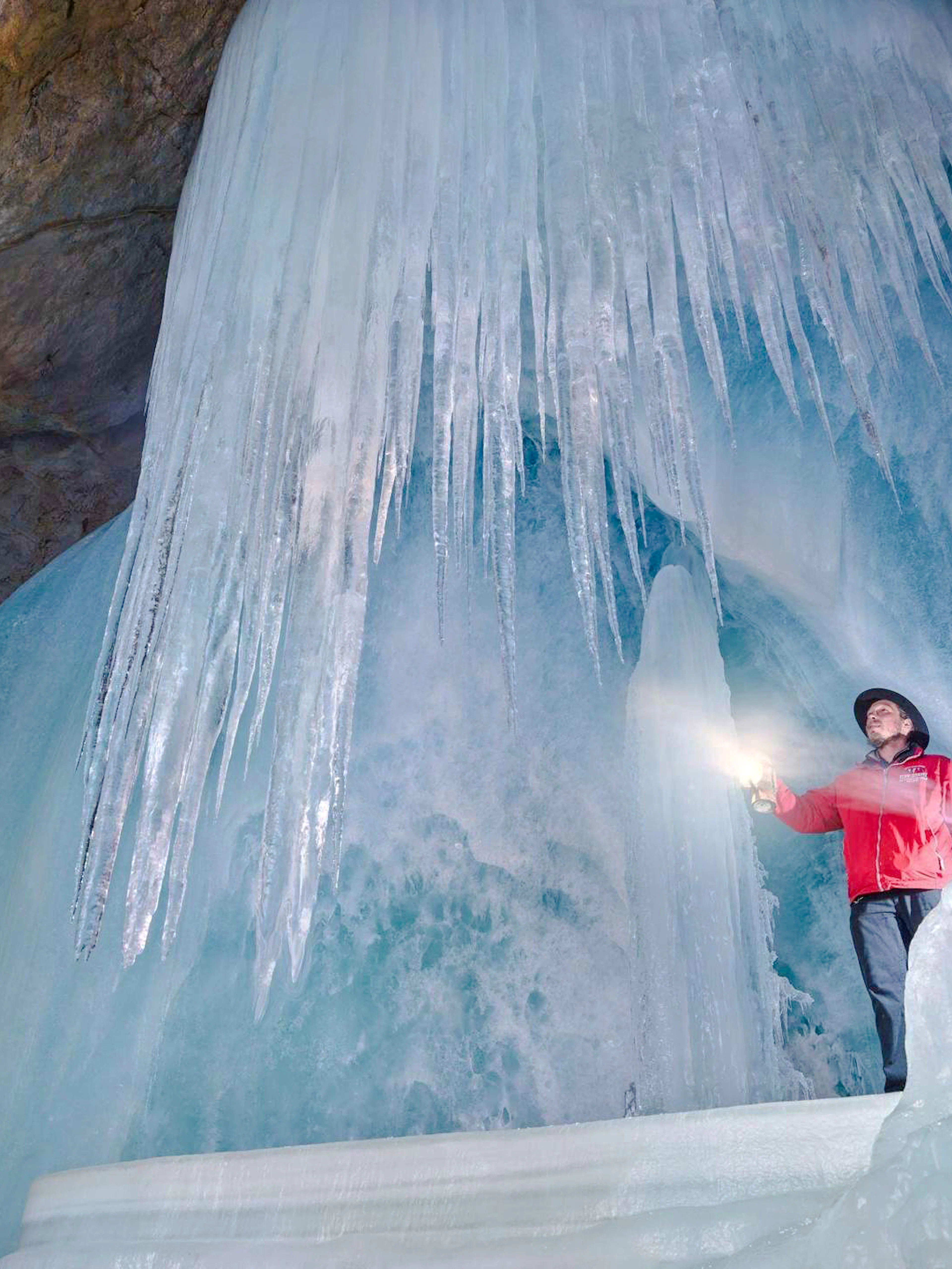 Person exploring Werfen Ice Caves with flashlight, Salzburg.