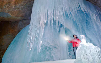 Person exploring Werfen Ice Caves with flashlight, Salzburg.