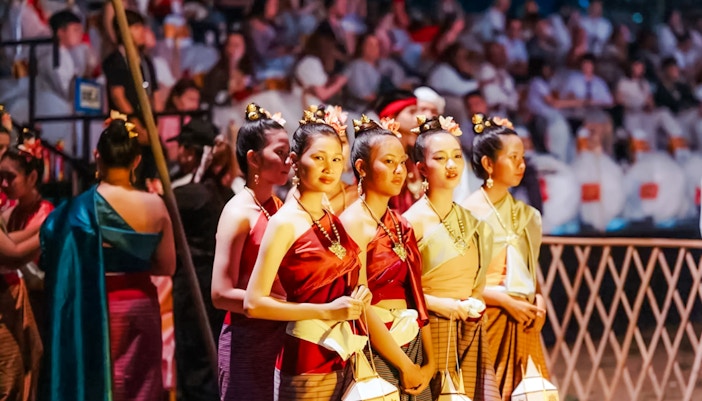 Yipeng Lantern Festival participant in traditional costume releasing lantern in Chiang Mai, Thailand.