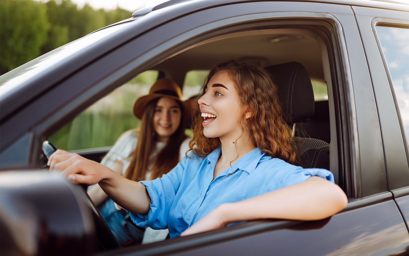 Two women smiling in a car during a road trip in Langkawi.