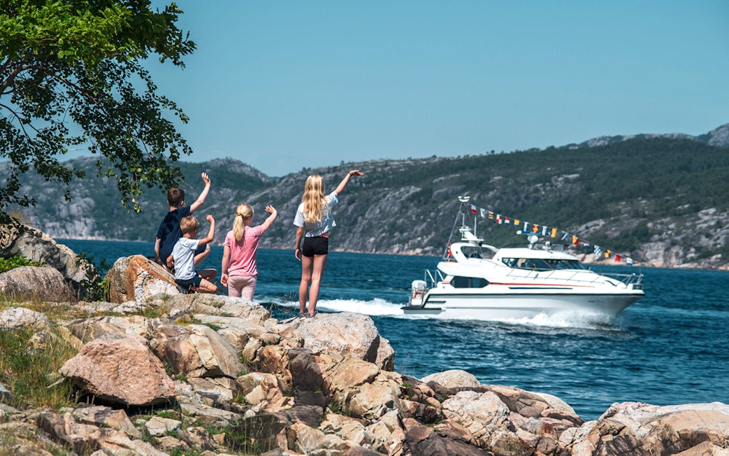Children waving at a boat on Lysefjord during a Fjordcruise to Preikestolen.