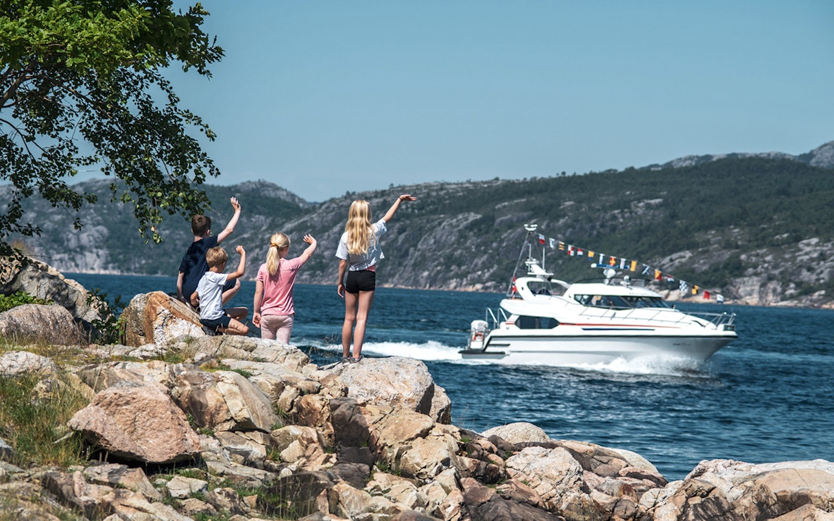 Children waving at a boat on Lysefjord during a Fjordcruise to Preikestolen.