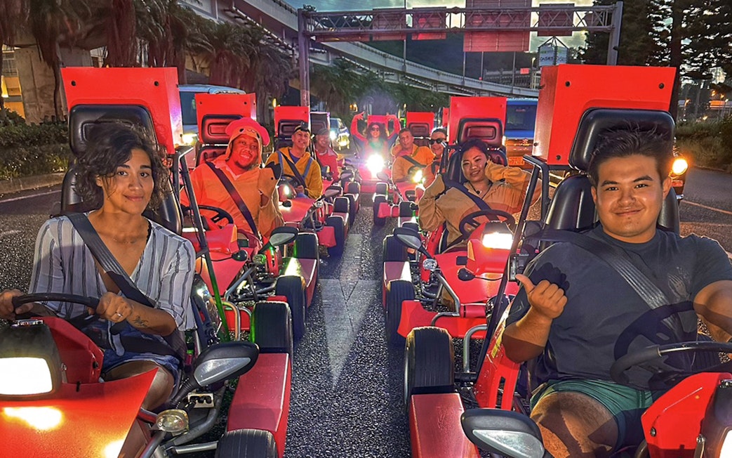 Group enjoying street go-karting in Okinawa at dusk.