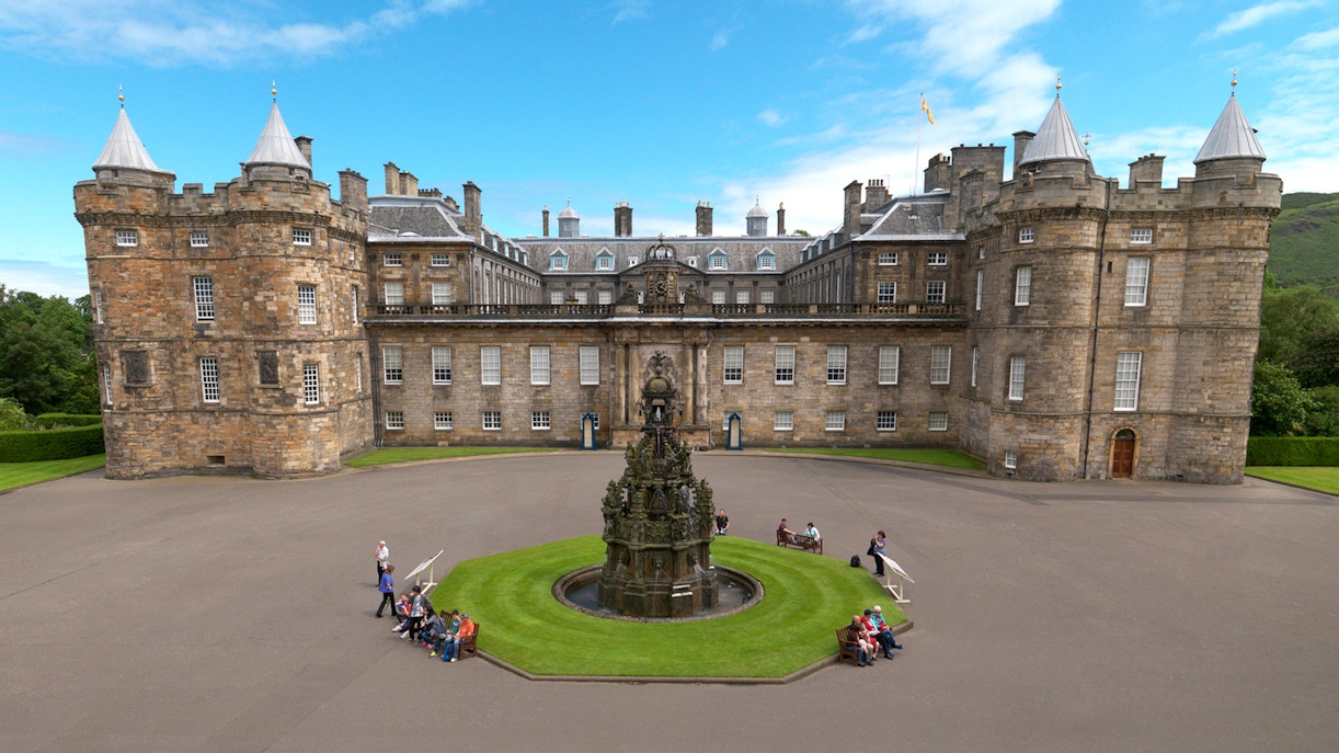 Palace of Holyroodhouse courtyard with fountain and visitors seated on benches.