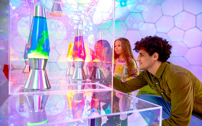 Visitors exploring colorful lava lamps at Bubble Planet exhibit, Washington DC.