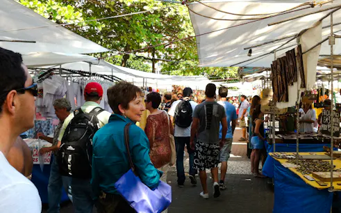 Visitors exploring Ipanema Street Market stalls with local crafts in Rio de Janeiro.