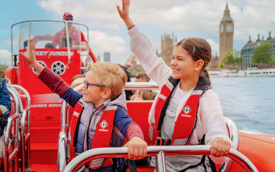 Children enjoying a Thames speed boat ride with Big Ben in the background.