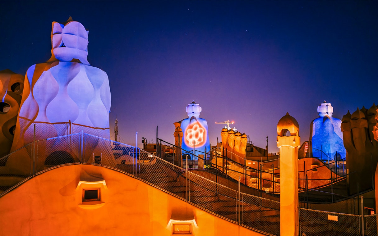 Casa Mila rooftop chimneys illuminated during La Pedrera Night Experience in Barcelona.