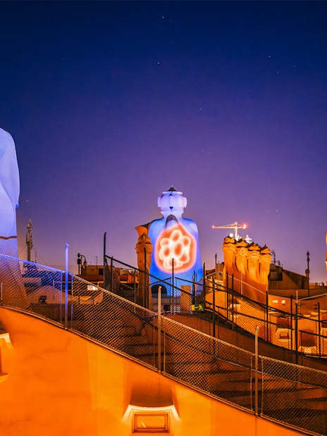 Casa Mila rooftop chimneys illuminated during La Pedrera Night Experience in Barcelona.