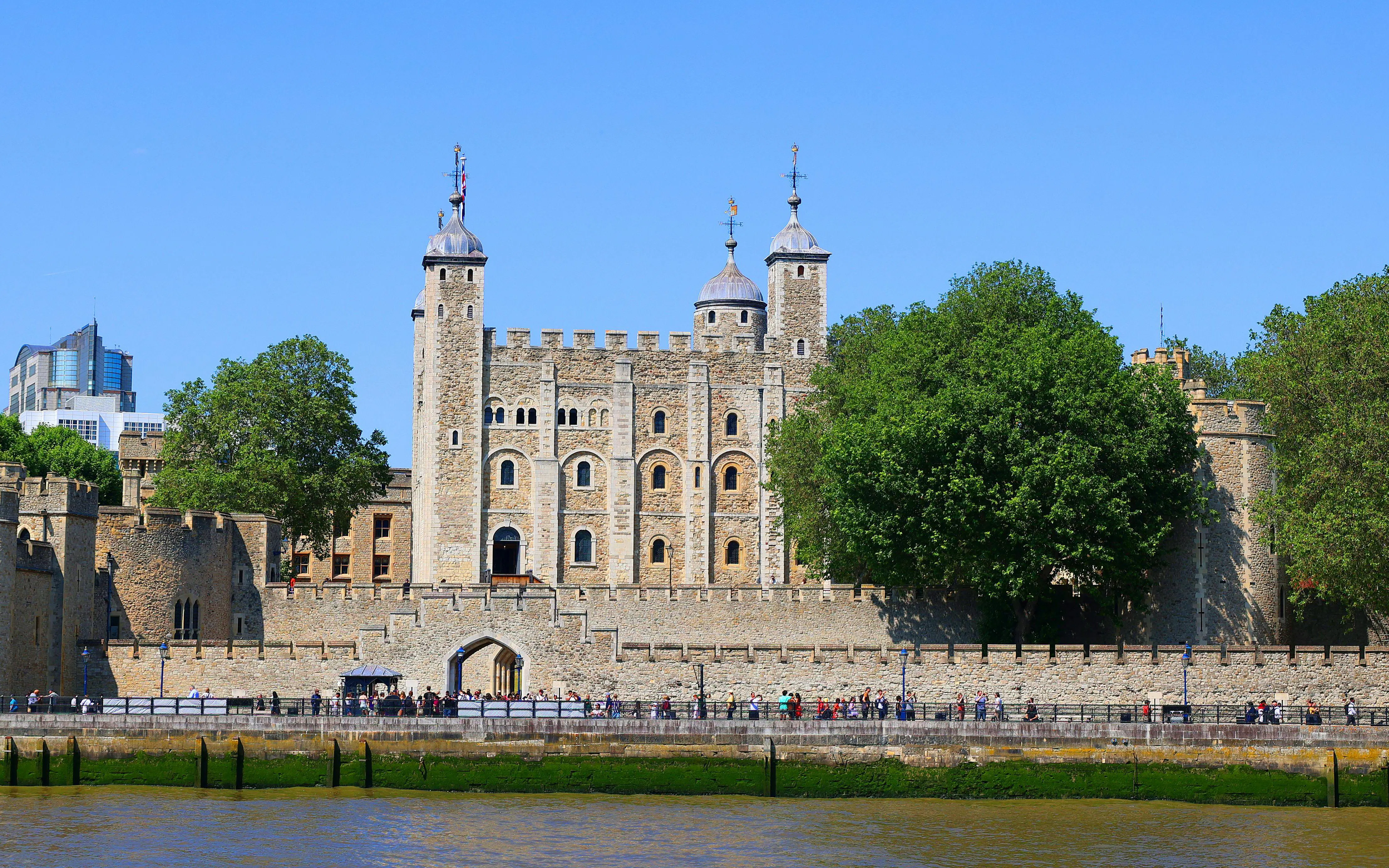 Tower of London with tourists along the Thames River, London, England.