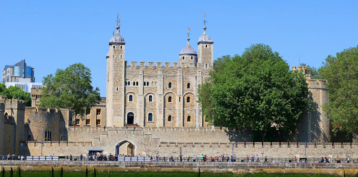 Tower of London with tourists along the Thames River, London, England.