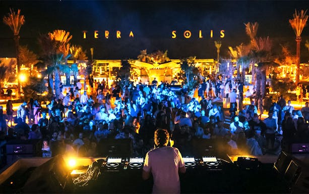 DJ performing at Terra Solis by Tomorrowland with a vibrant crowd at night.