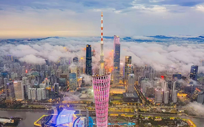 Canton Tower illuminated at dusk with clouds over Guangzhou skyline.