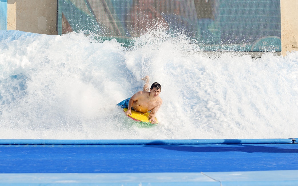 Surfer riding artificial wave at Yas Waterworld Abu Dhabi.