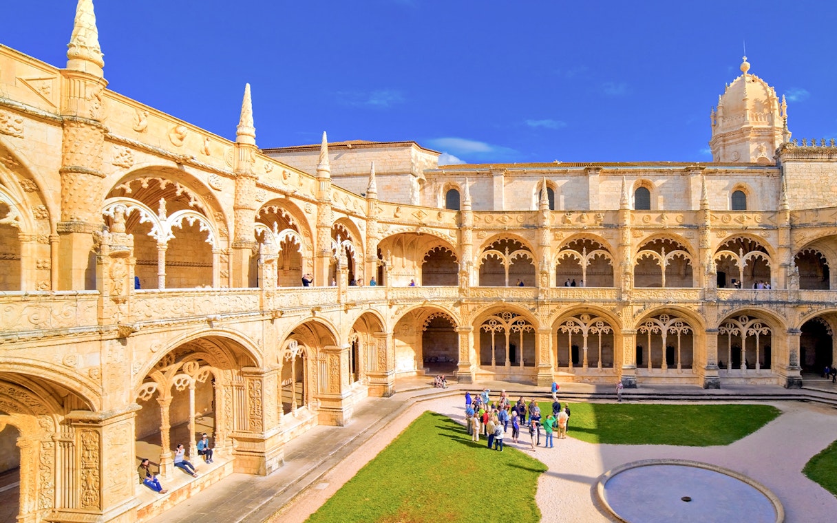 Jernimos Monastery courtyard with tourists on a guided walking tour in Lisbon, Portugal.