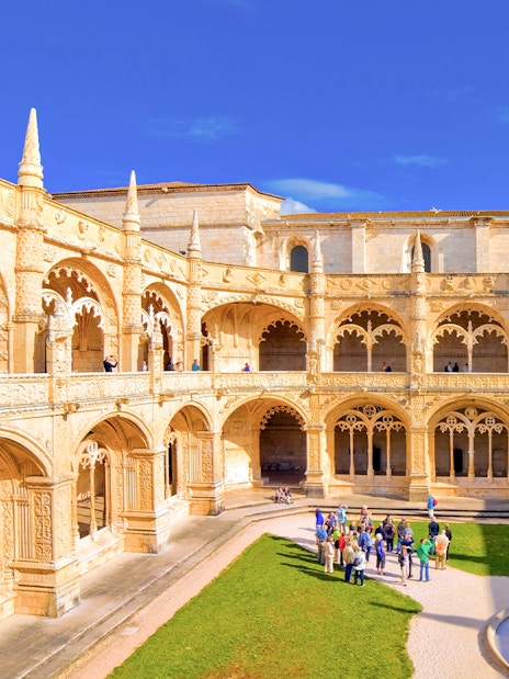 Jernimos Monastery courtyard with tourists on a guided walking tour in Lisbon, Portugal.