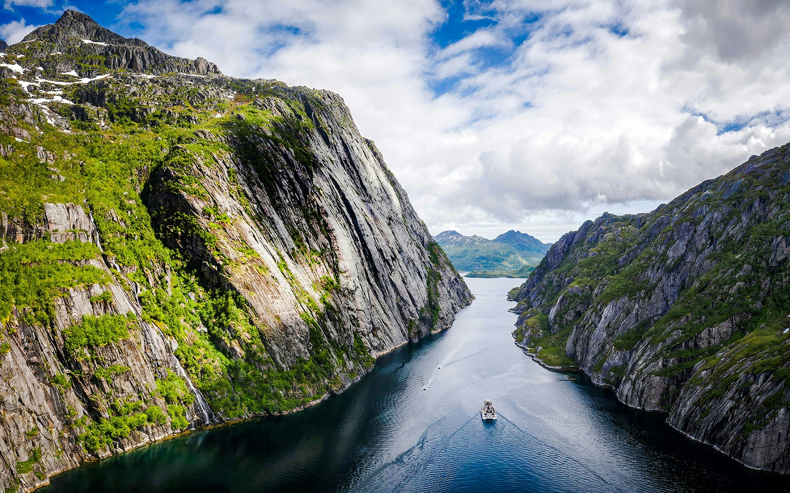 Aerial view of a boat cruising through Trollfjord, surrounded by steep cliffs in Lofoten.