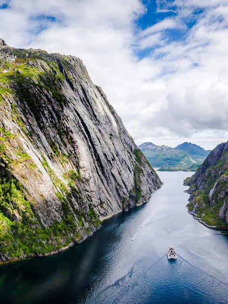 Aerial view of a boat cruising through Trollfjord, surrounded by steep cliffs in Lofoten.