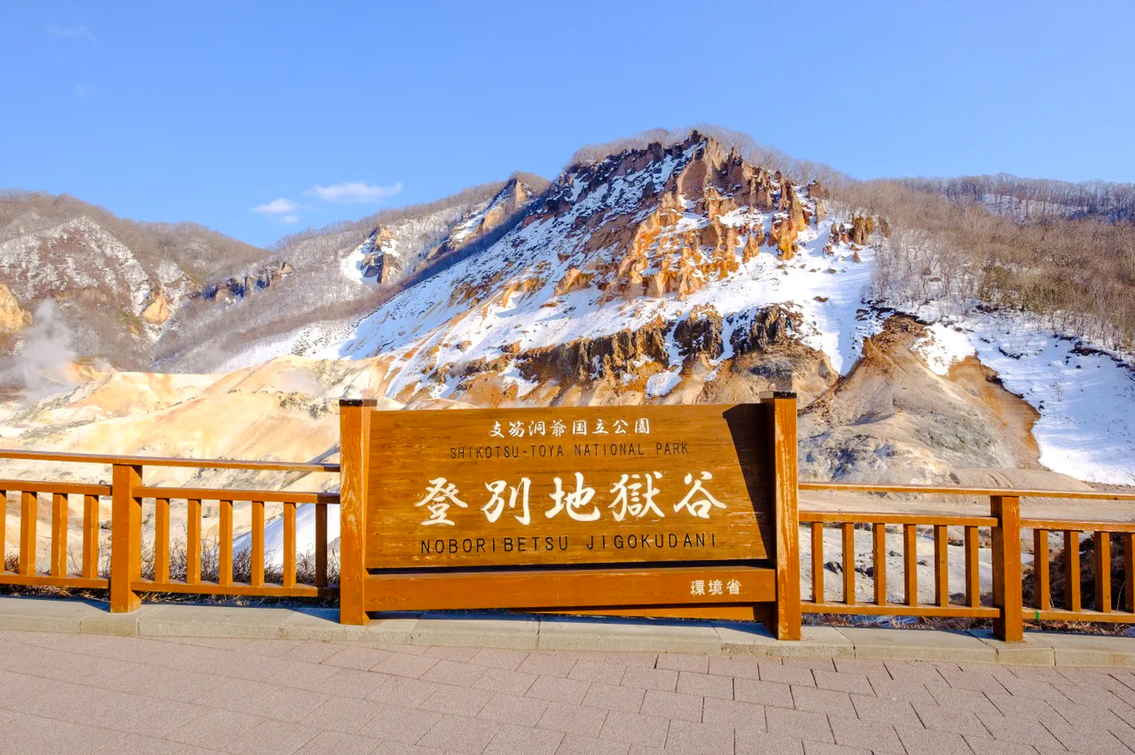 Noboribetsu Hell Valley sign with snow-covered volcanic landscape, Hokkaido.