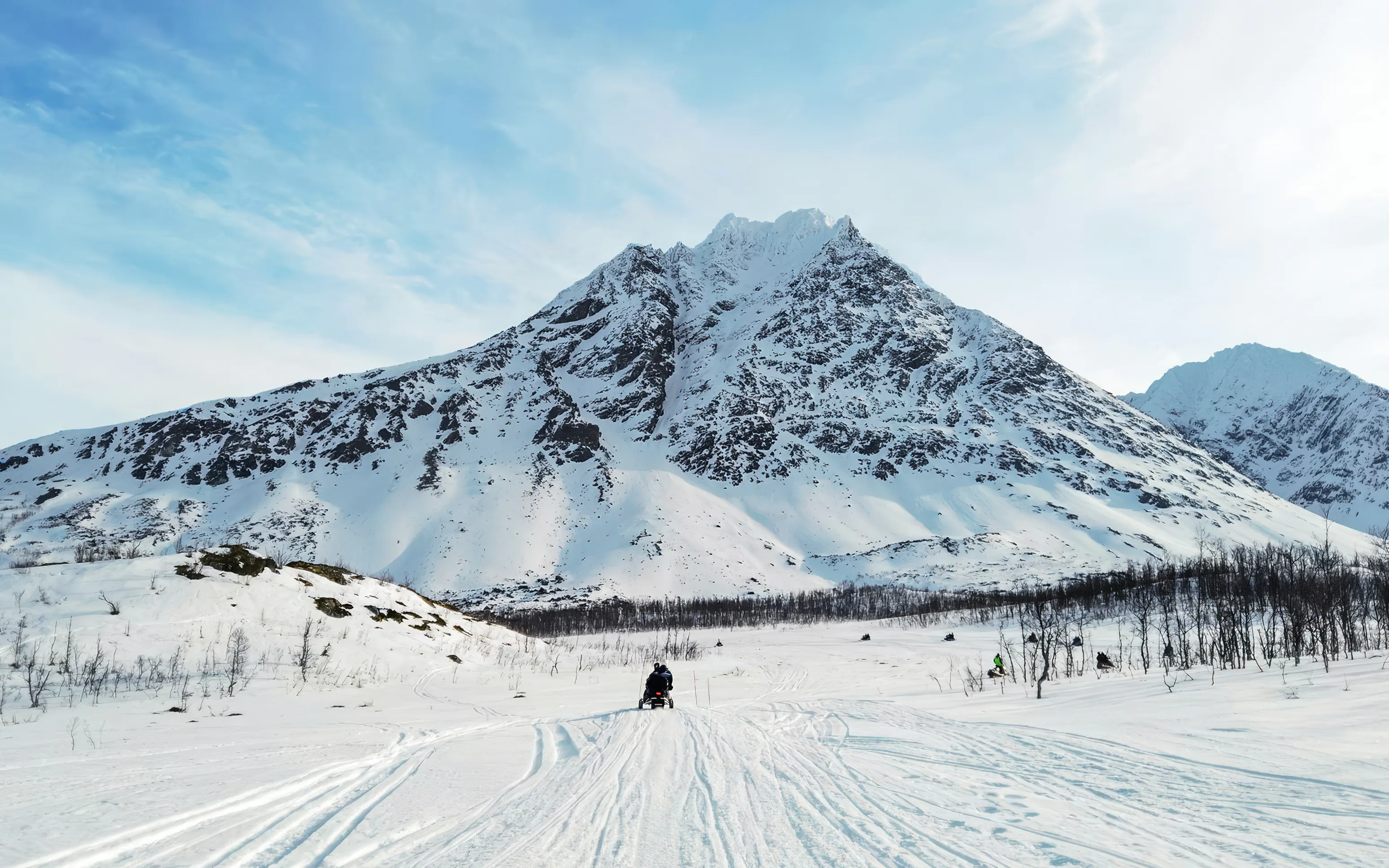 Snowmobile rider in the Lyngen Alps, Tromsø, with snowy mountain backdrop.
