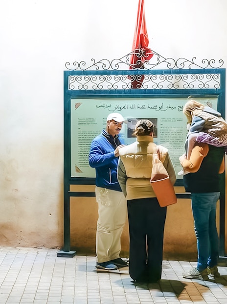 Tour guide explaining a sign to visitors during a Marrakech night walking tour.