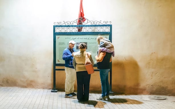 Tour guide explaining a sign to visitors during a Marrakech night walking tour.