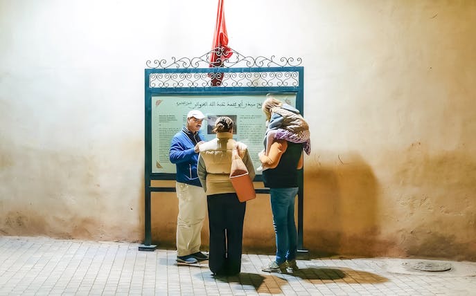 Tour guide explaining a sign to visitors during a Marrakech night walking tour.