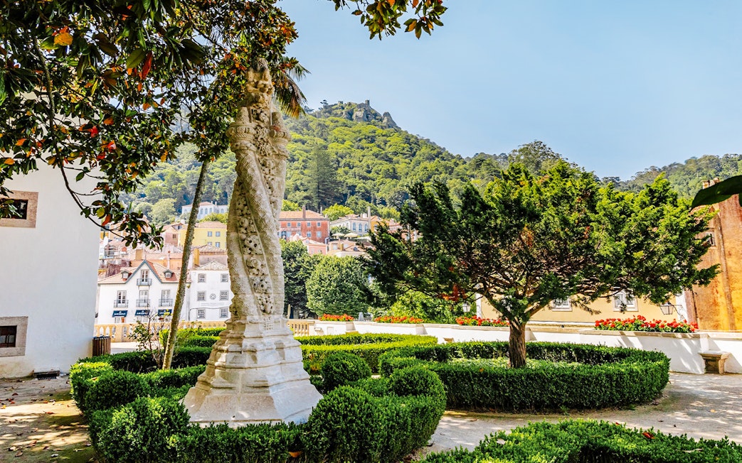 Sintra National Palace Gardens with ornate column and lush greenery.