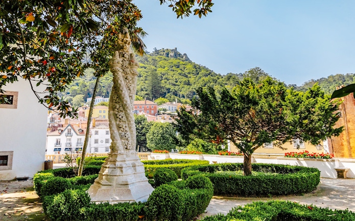 Sintra National Palace Gardens with ornate column and lush greenery.
