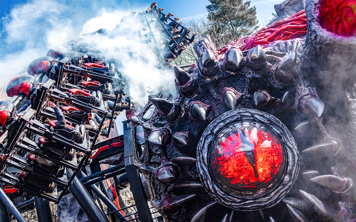 Roller coaster on Nemesis Reborn ride at Alton Towers with dramatic smoke effects.