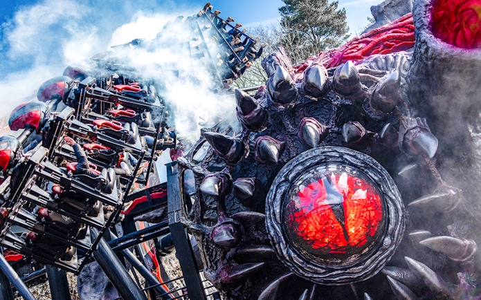 Roller coaster on Nemesis Reborn ride at Alton Towers with dramatic smoke effects.