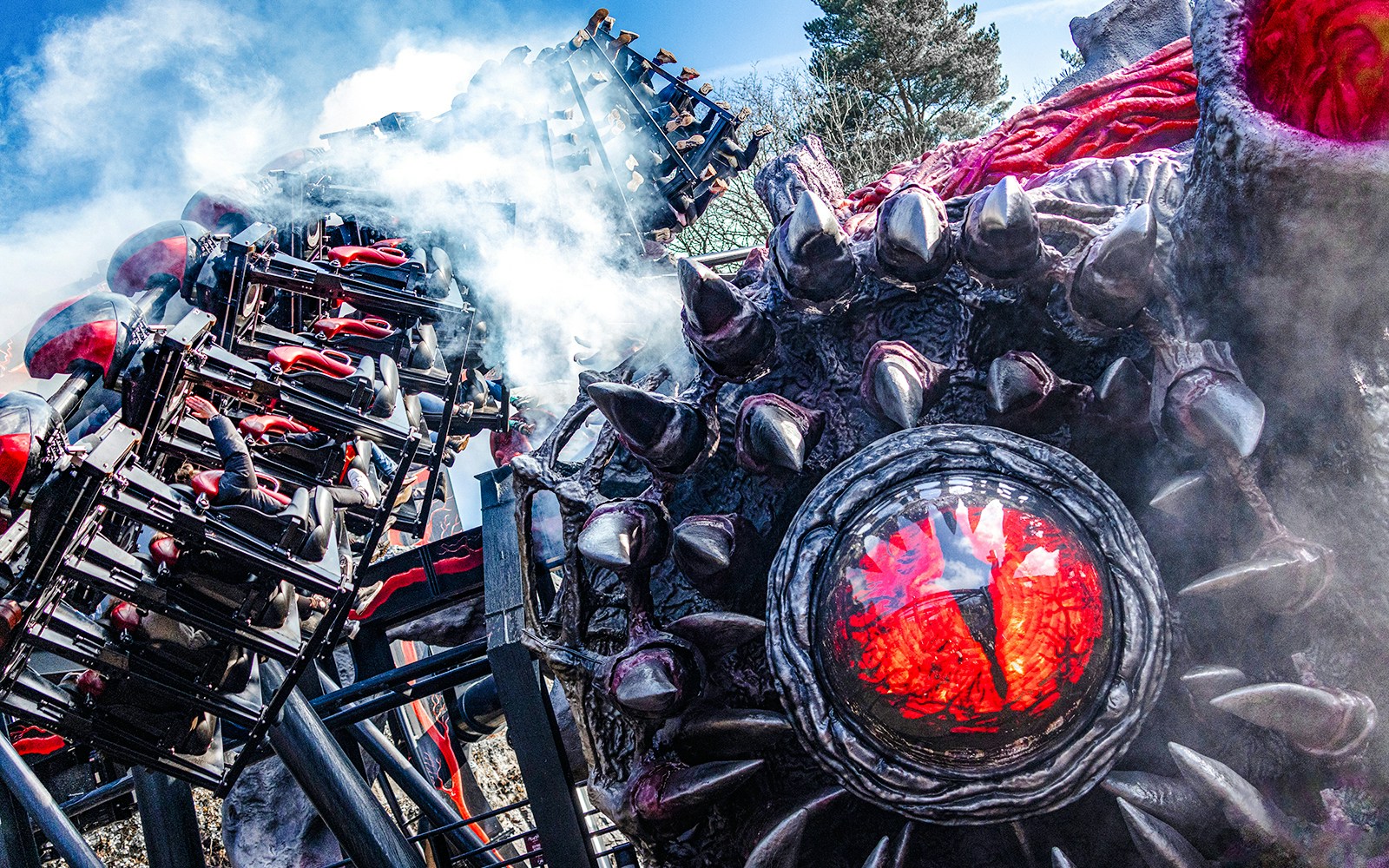 Roller coaster on Nemesis Reborn ride at Alton Towers with dramatic smoke effects.