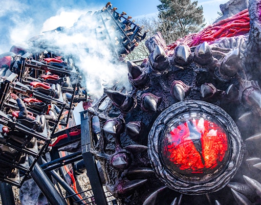 Roller coaster on Nemesis Reborn ride at Alton Towers with dramatic smoke effects.
