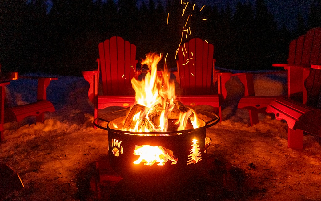 Bonfire surrounded by red chairs in snowy Zakopane during snowmobile tour.