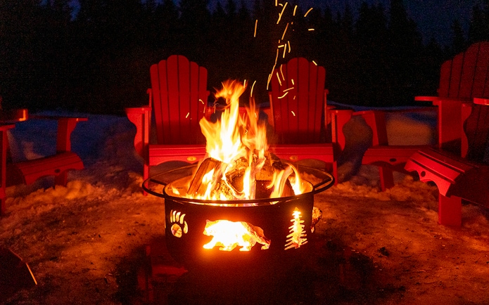 Bonfire surrounded by red chairs in snowy Zakopane during snowmobile tour.
