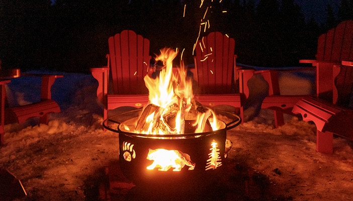 Bonfire surrounded by red chairs in snowy Zakopane during snowmobile tour.