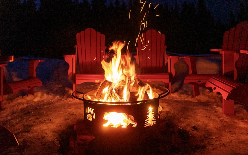 Bonfire surrounded by red chairs in snowy Zakopane during snowmobile tour.