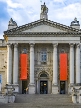 Tate Britain entrance with neoclassical columns and red banners, London.