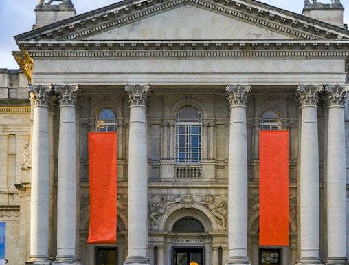Tate Britain entrance with neoclassical columns and red banners, London.