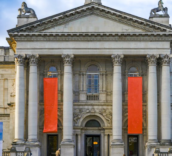Tate Britain entrance with neoclassical columns and red banners, London.