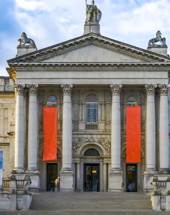 Tate Britain entrance with neoclassical columns and red banners, London.