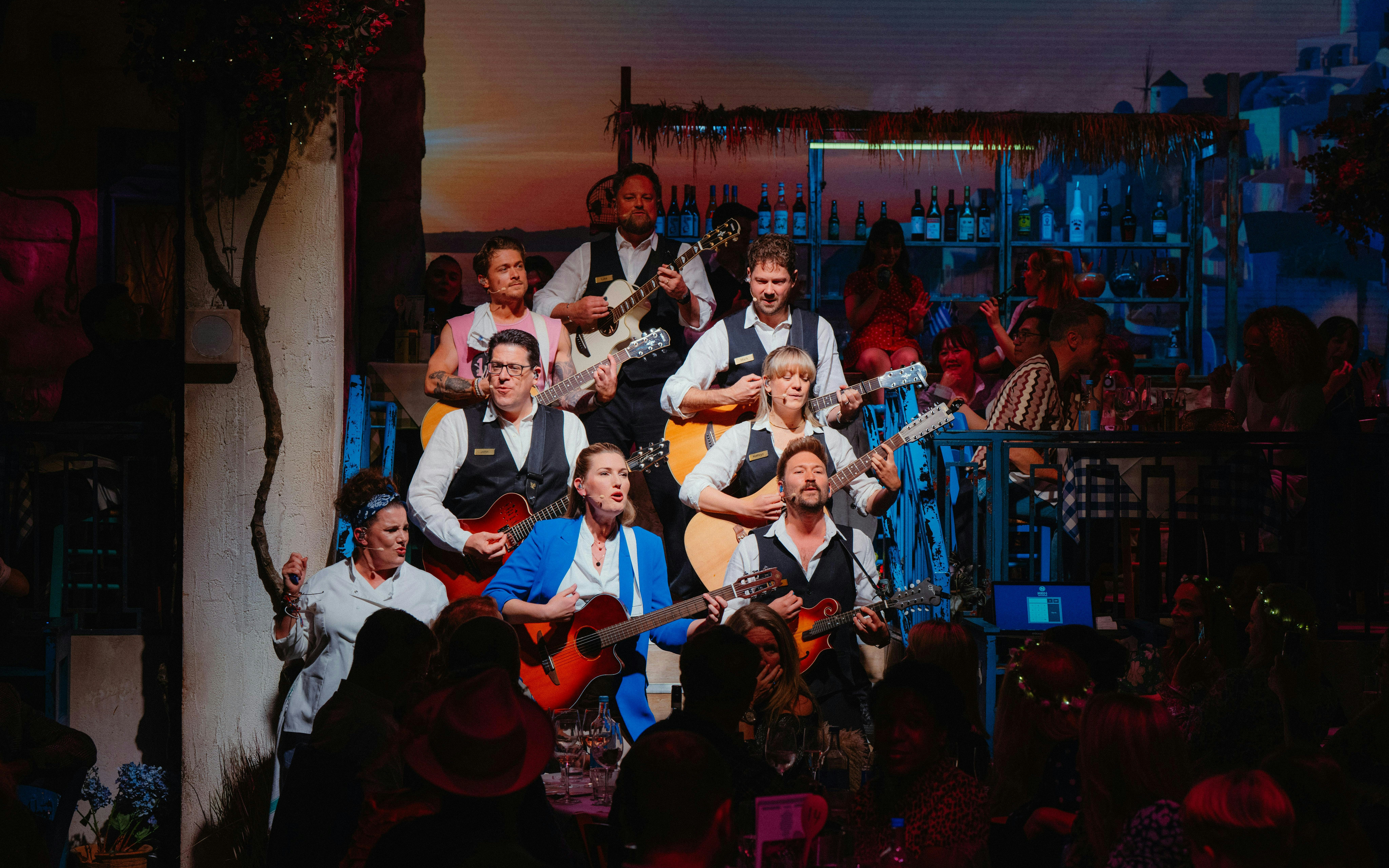 Performers playing guitars during Mamma Mia! The Party show.