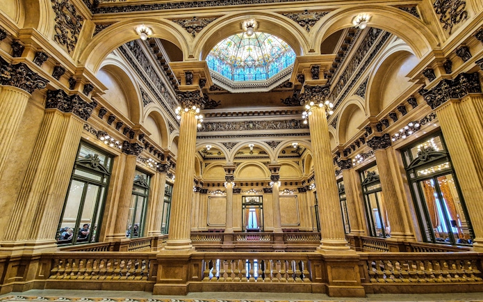 Interior of Teatro Colon, showcasing ornate columns and stained glass ceiling in Buenos Aires, Argentina.