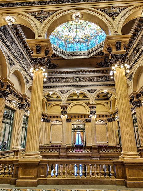 Interior of Teatro Colon, showcasing ornate columns and stained glass ceiling in Buenos Aires, Argentina.