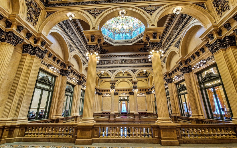 Interior of Teatro Colon, showcasing ornate columns and stained glass ceiling in Buenos Aires, Argentina.