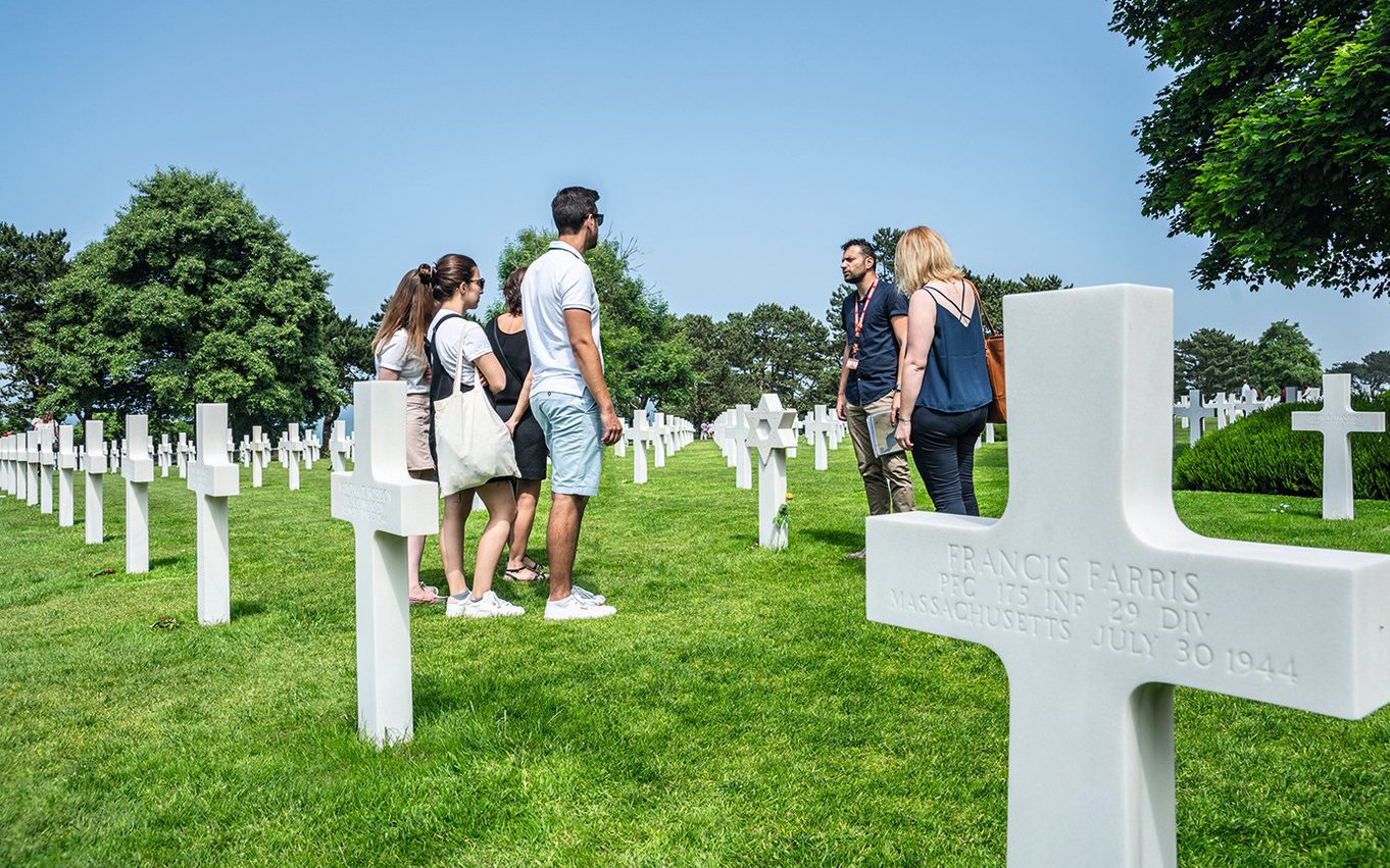 Group tour at Normandy American Cemetery with guide among white crosses.