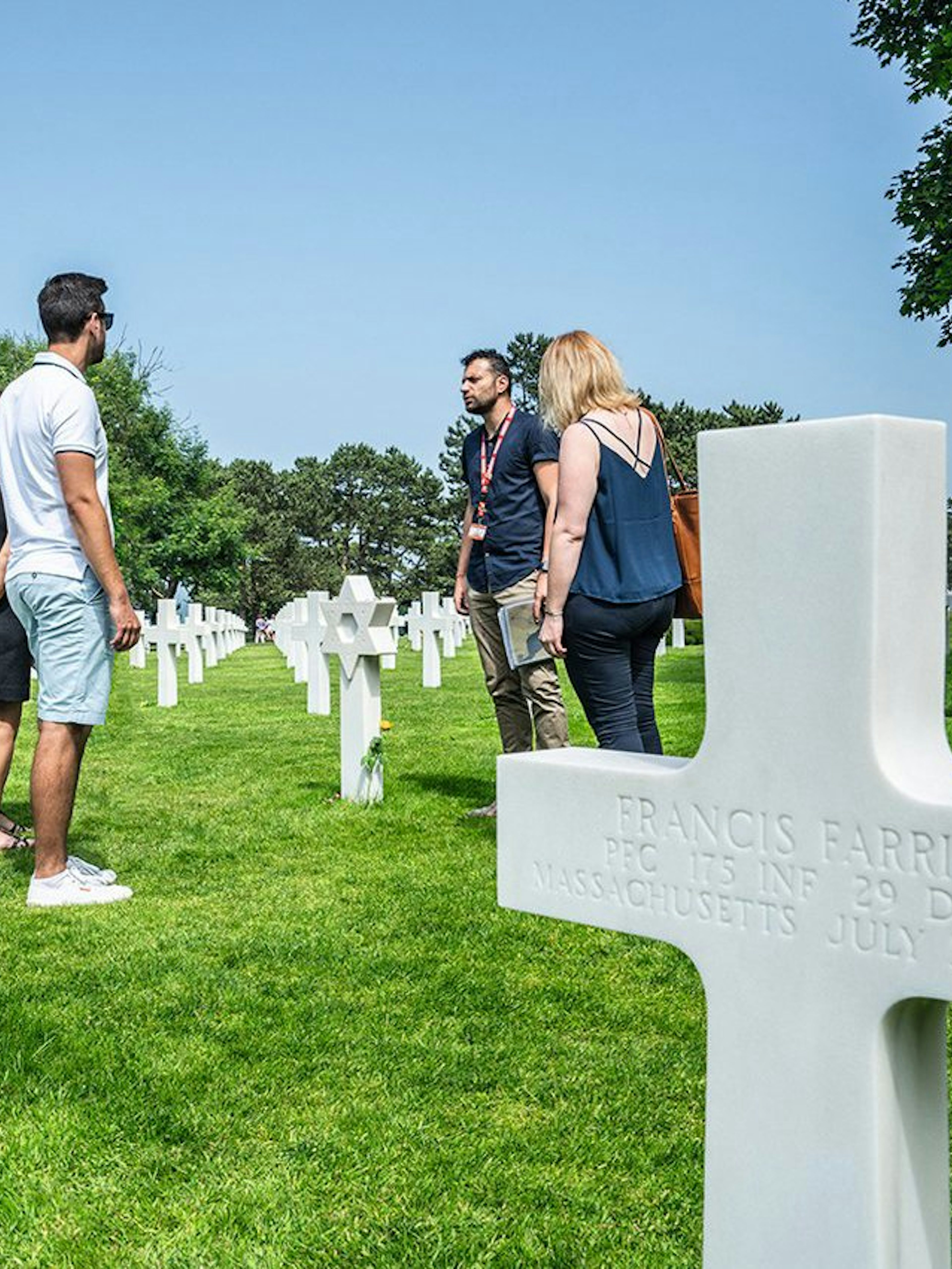 Group tour at Normandy American Cemetery with guide among white crosses.